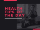 Person stretching on a yoga mat indoors with the text "Health Tips of the Day" in bold red letters.