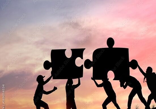 Silhouettes of people working together to fit giant puzzle pieces against a sunset background, embodying the spirit of challenges and personality development.