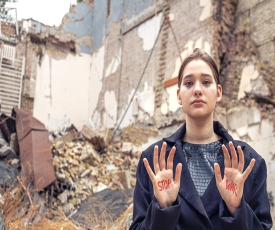 Why Did Israel Use an Earthquake Bomb on Syria? 1 In front of a pile of rubble from a destroyed building, a person stands with "Stop War" written on their hands, symbolically opposing the devastation left in the wake of an airstrike.
