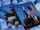 Stack of books titled "Save America" with a cover image featuring a man holding an American flag against a background of blue hydrangeas.